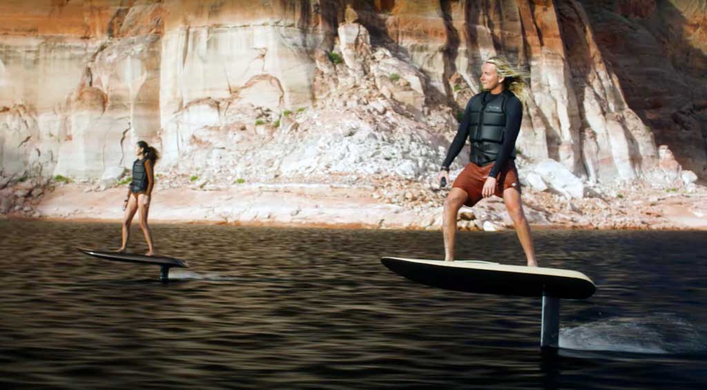 Couple enjoying e-foil hydrofoil surfing on crystal-clear waters